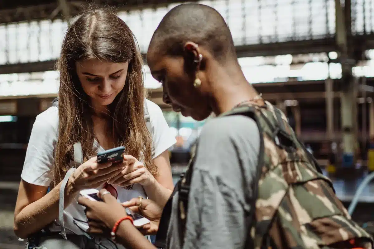 Mains tenant un téléphone affichant une application de réservation de vols et un carnet de budget voyage