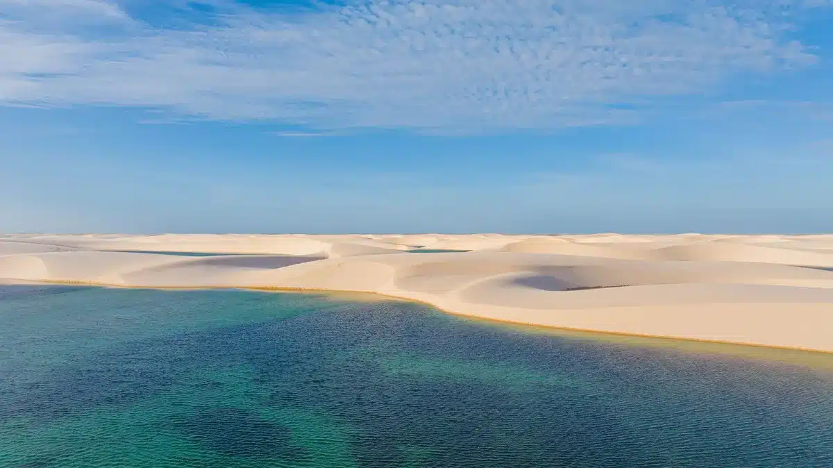 Plage de sable blanc avec lagon turquoise et végétation tropicale en arrière-plan