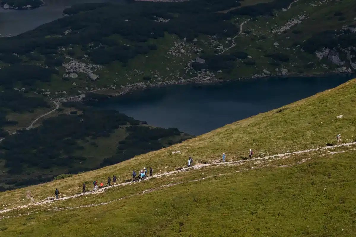 Foules de touristes dans une vallée alpine entourée de montagnes enneigées