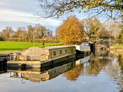 Péniche naviguant paisiblement sur un canal bordé d'arbres, avec une tour médiévale en arrière-plan