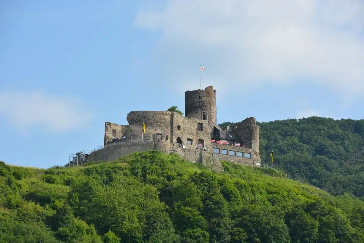 Château médiéval perché sur une colline boisée, accessible par un sentier cyclable