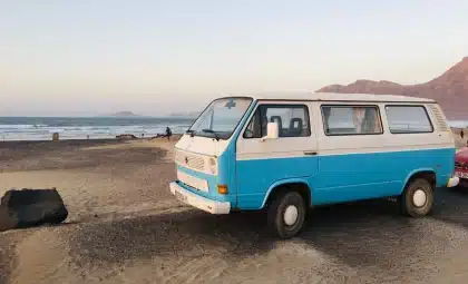 Camping-car roulant sur une route désertique avec paysage de falaises rocheuses en arrière-plan