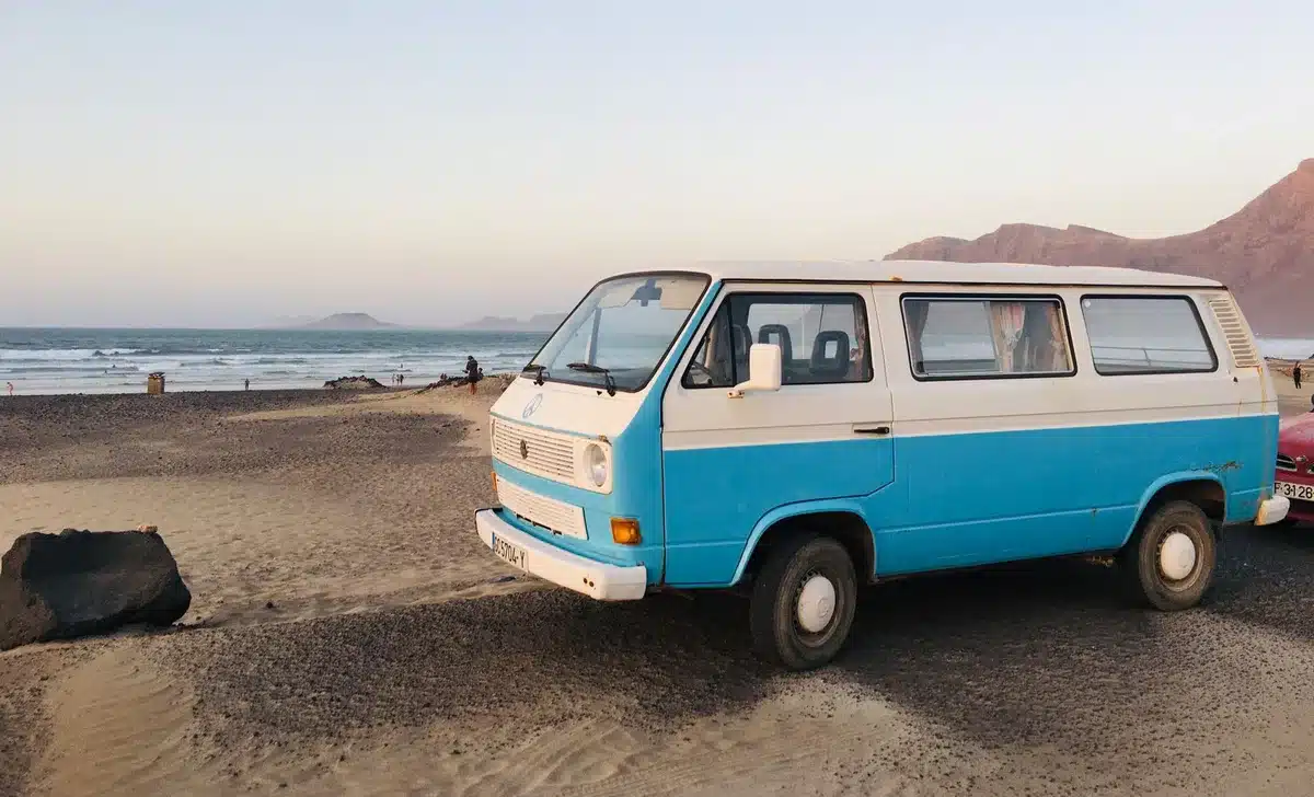 Camping-car roulant sur une route désertique avec paysage de falaises rocheuses en arrière-plan