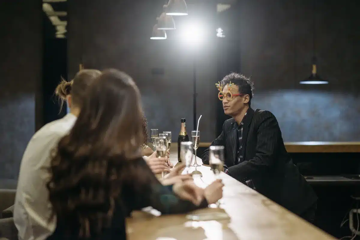 Groupe de personnes levant leurs verres autour d'un comptoir de bar dans une ambiance chaleureuse