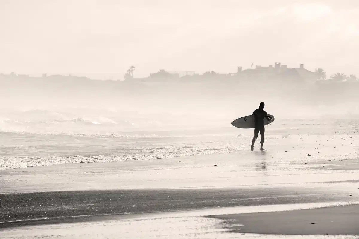 Surfeurs sur une grande plage de sable avec des vagues de l'océan Pacifique