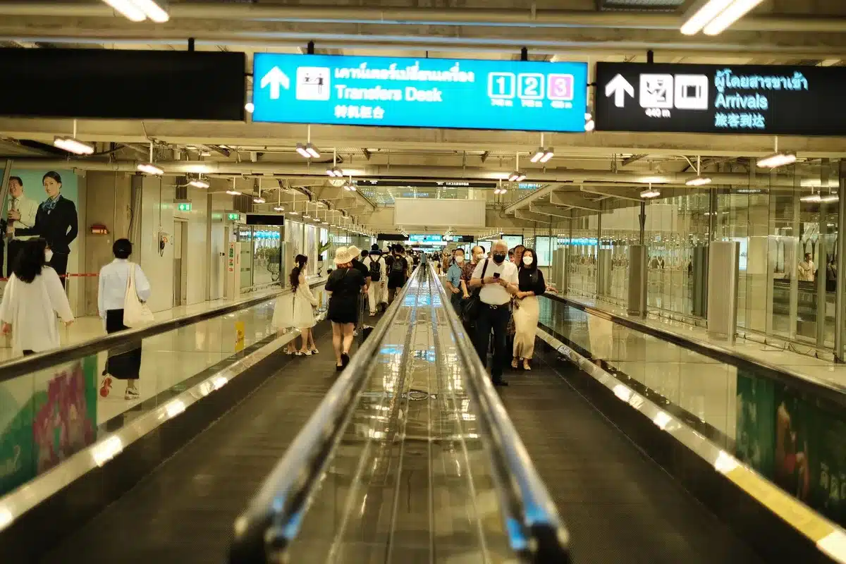 Voyageurs anonymes dans un terminal d'aéroport international, représentant les flux touristiques mondiaux.