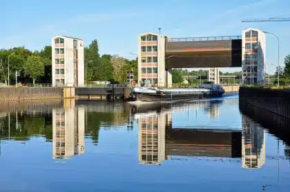 Péniche naviguant sur un canal historique avec écluse et paysage rural verdoyant