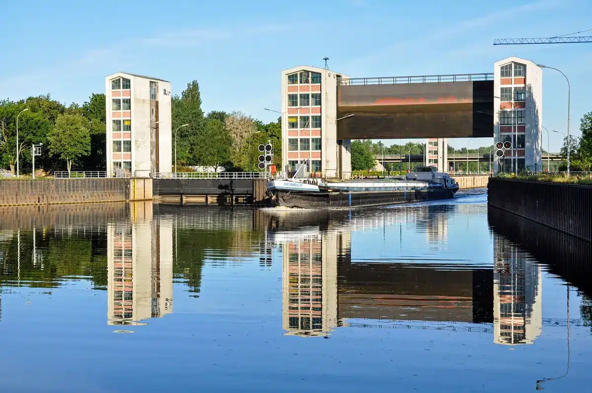 Péniche naviguant sur un canal historique avec écluse et paysage rural verdoyant