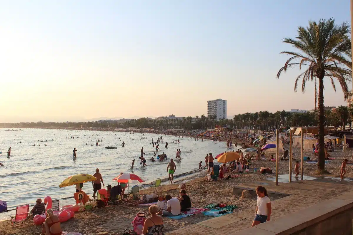 Plage espagnole ensoleillée avec touristes, illustrant la progression de l'Espagne au top 20