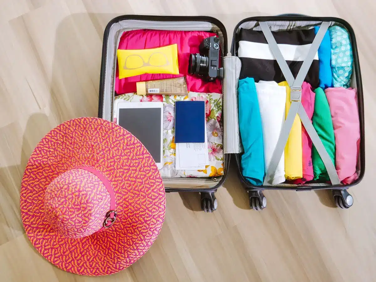 Valise ouverte avec vêtements, serviette et accessoires de plage soigneusement rangés