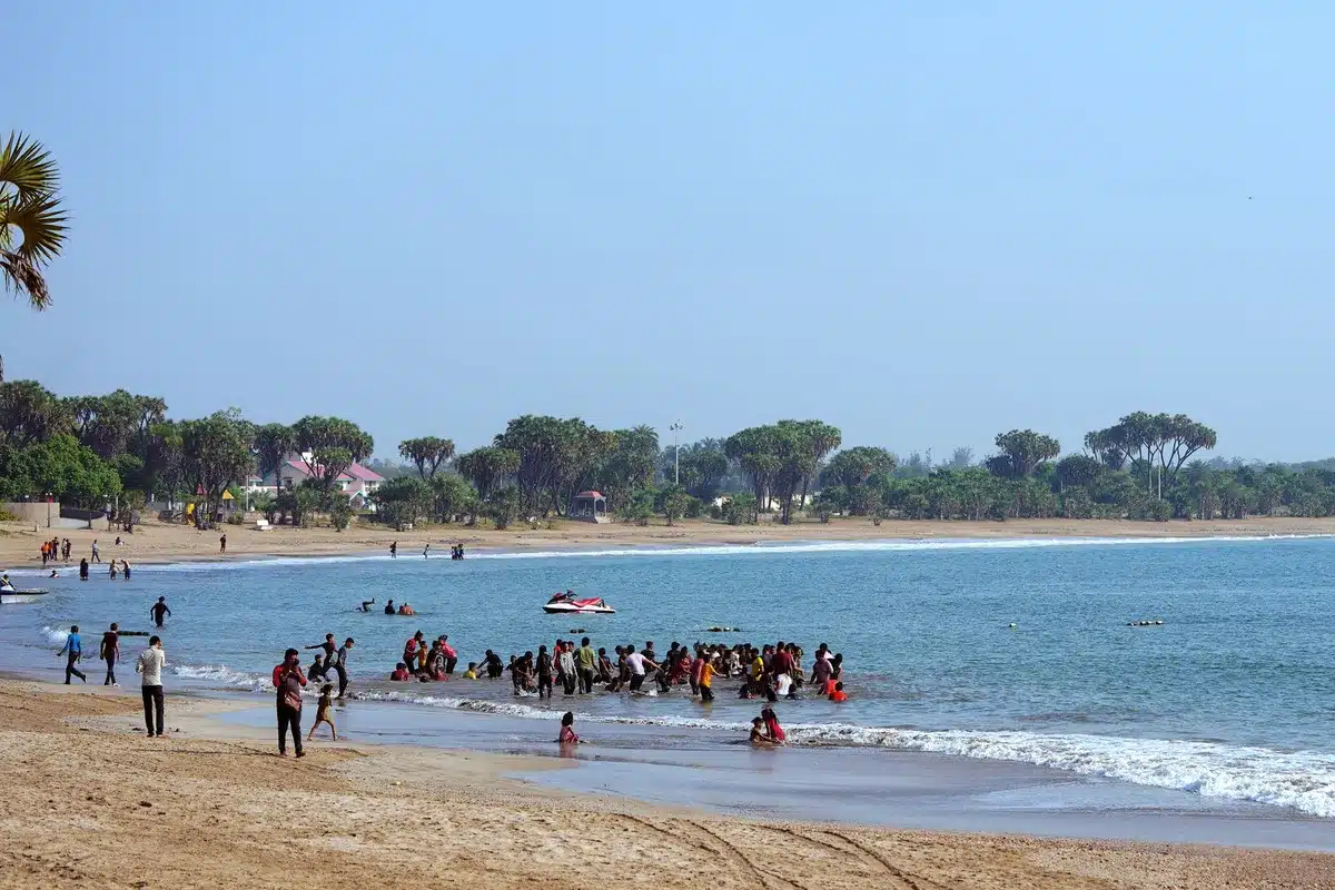 Famille en maillot jouant et nageant ensemble sur une plage ensoleillée