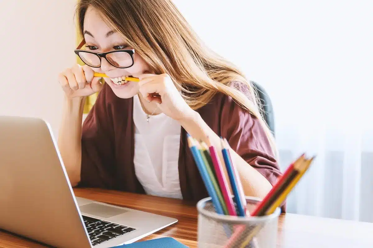 Personne étudiant l'anglais à un bureau avec un ordinateur portable et des notes de cours