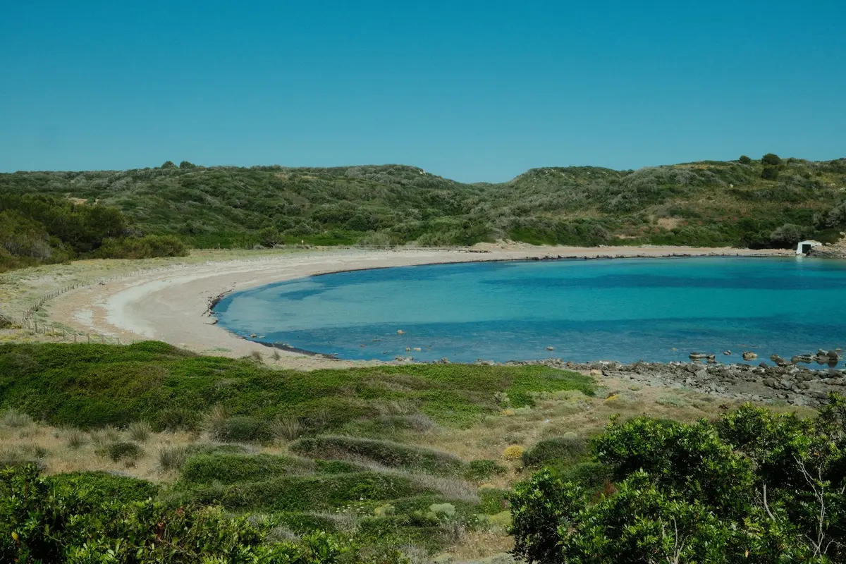Plage de sable fin avec eaux cristallines et falaises en arrière-plan