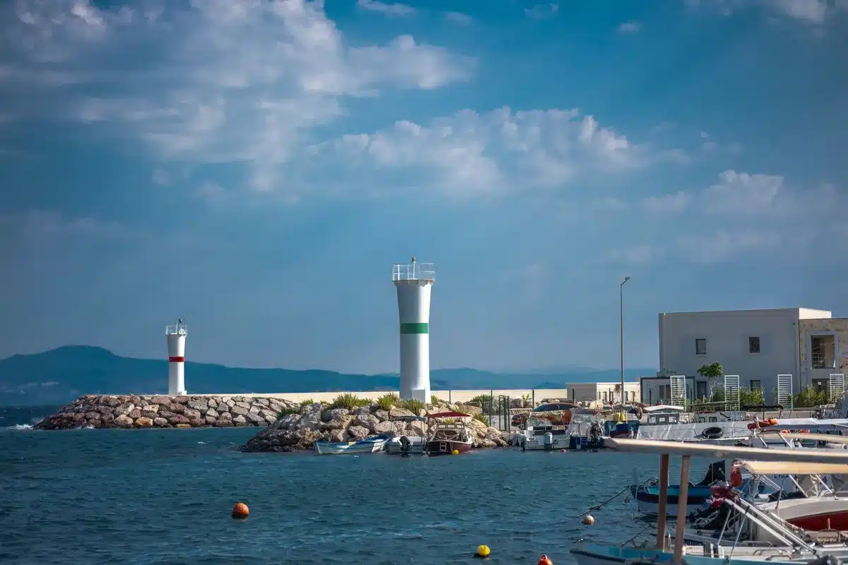 Phare au bout d'une jetée rocheuse avec vue sur la mer calme et le port