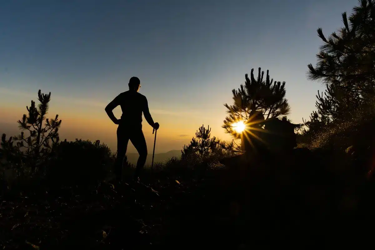 Randonneur sur un sentier montagneux avec lumière dorée du matin