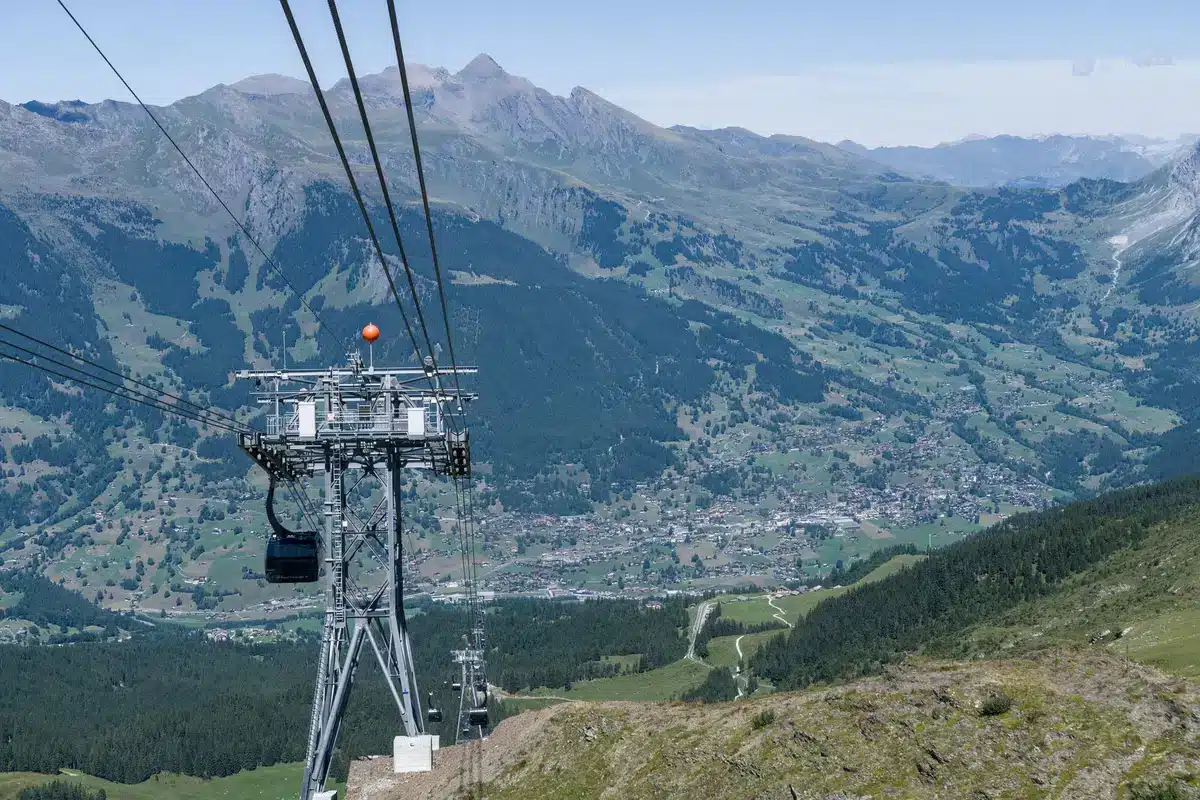 Vue aérienne d'une vallée alpine avec village coloré entouré de forêts et de sommets