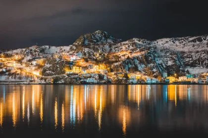 Falaises côtières de Terre-Neuve avec village aux maisons colorées et iceberg en mer
