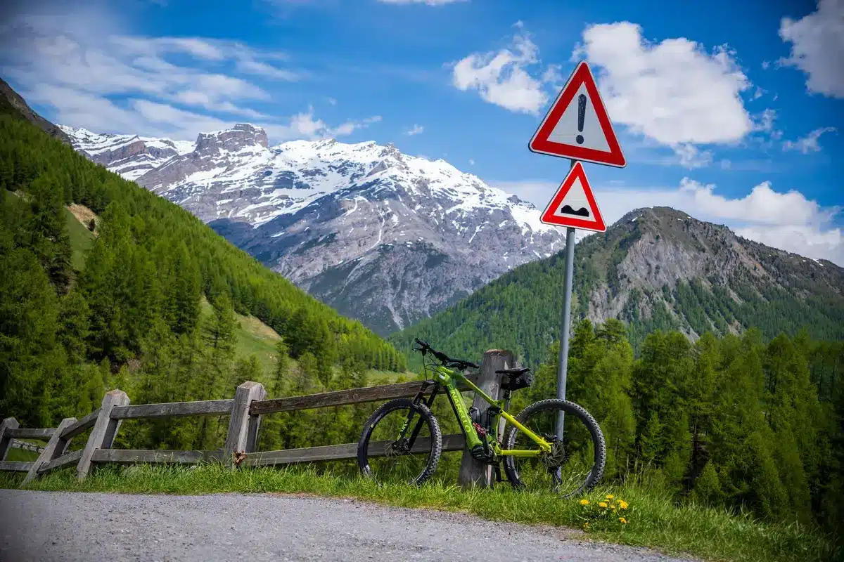 Cycliste sur un sentier panoramique dans une vallée alpine avec forêts et montagnes