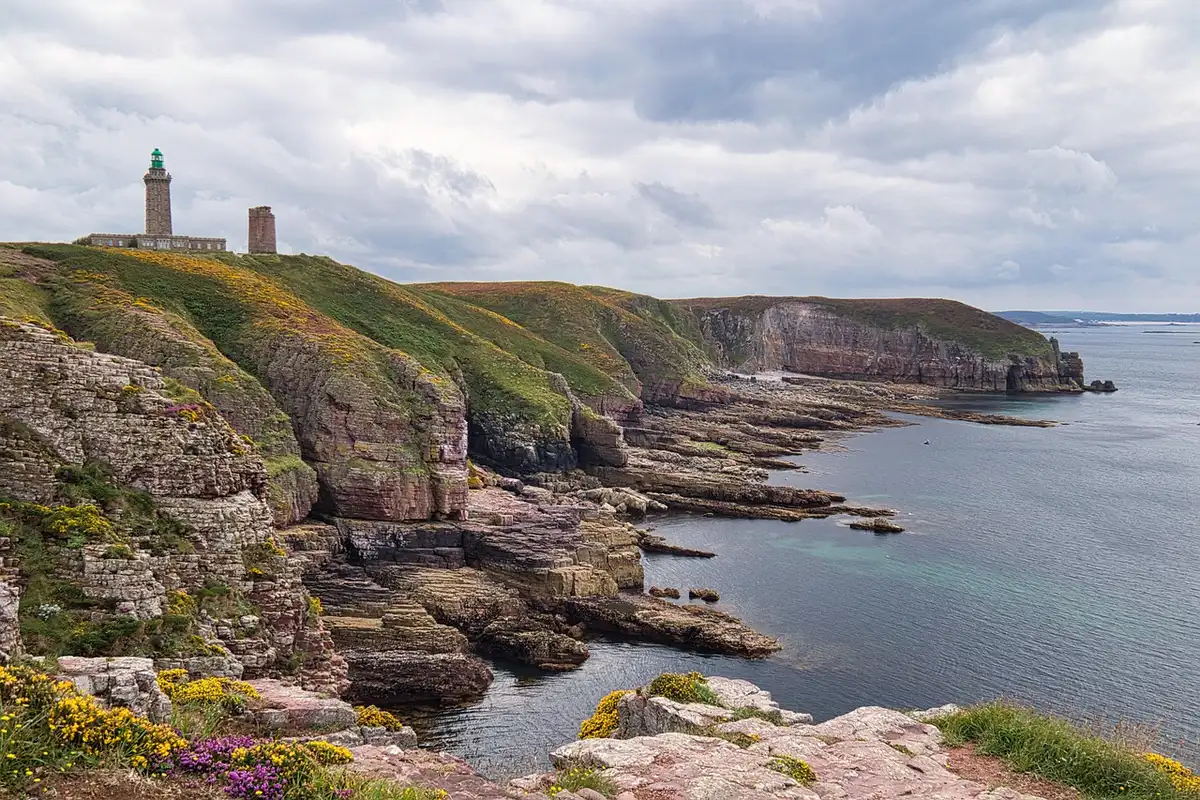 Falaises rocheuses du Cap Fréhel avec phare en arrière-plan