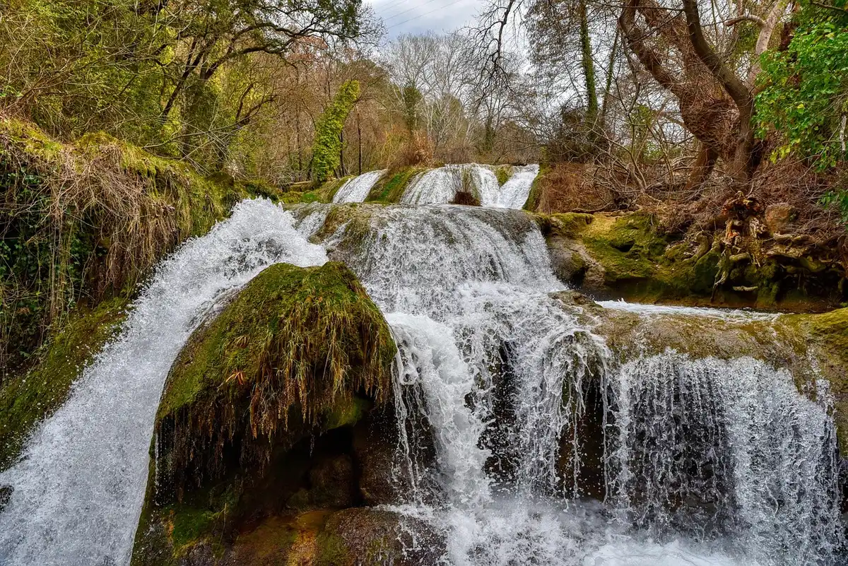 Cascade spectaculaire entourée de falaises calcaires et forêt dense