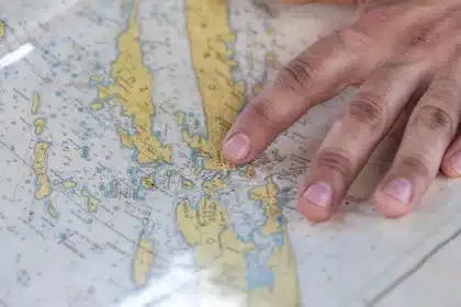 Table de pique-nique au bord de l'eau avec carte, guidon de vélo et catamaran flou en arrière-plan