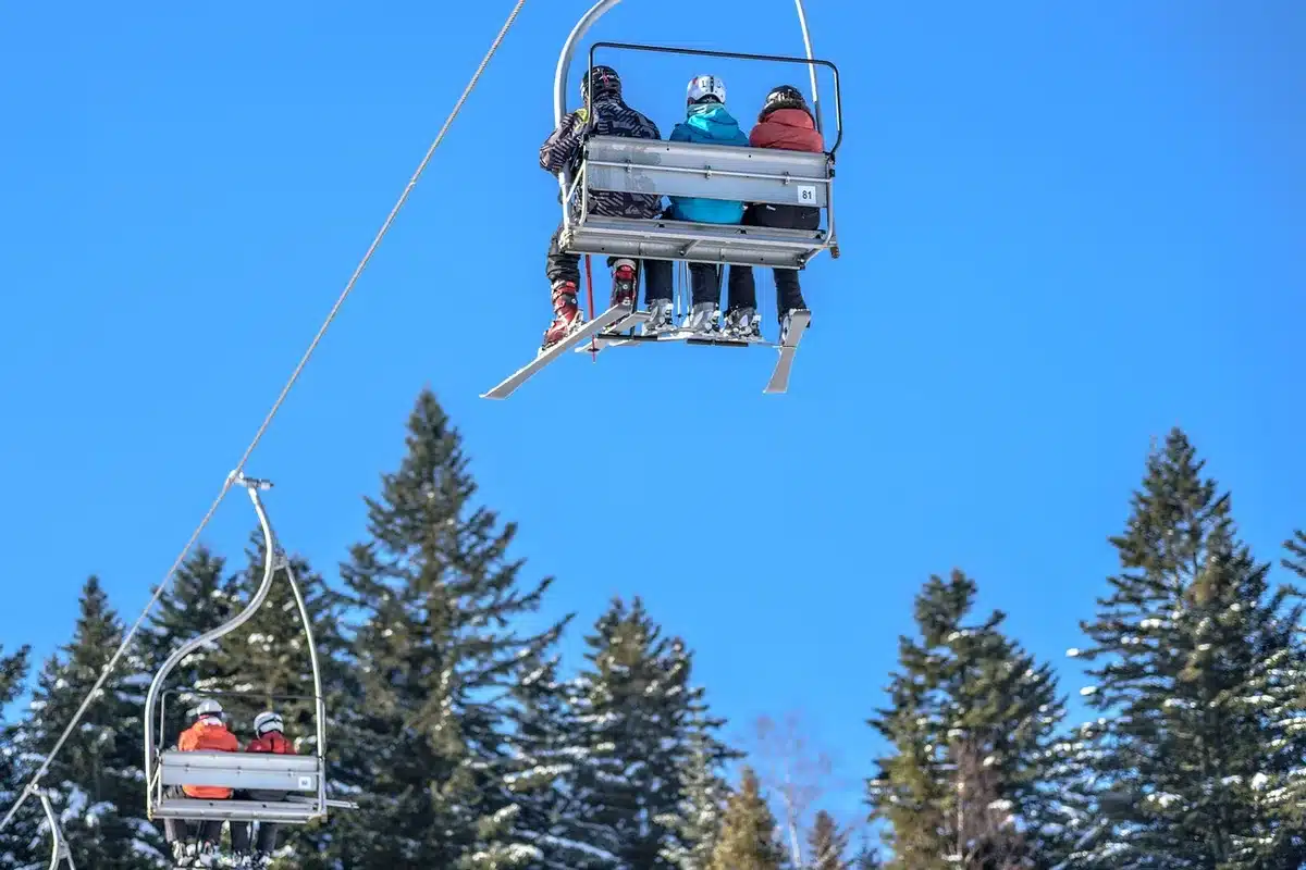 Skieurs descendant les pistes enneigées d'une station de montagne avec panorama alpin en arrière-plan