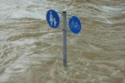 Vallée montagneuse endommagée par les crues, avec des eaux boueuses et une équipe de secours en arrière-plan