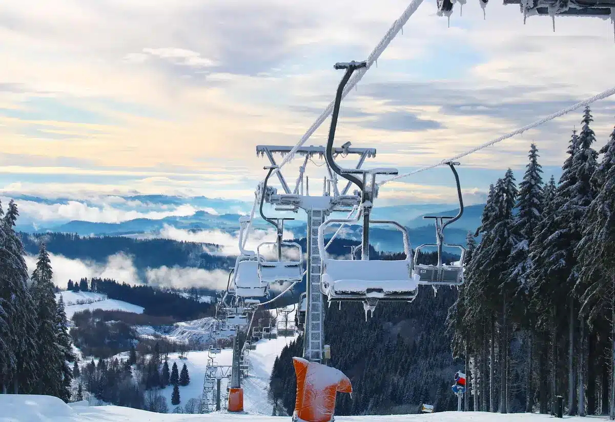 Skieur descendant une piste large de station alpine en hiver avec montagnes enneigées en arrière-plan