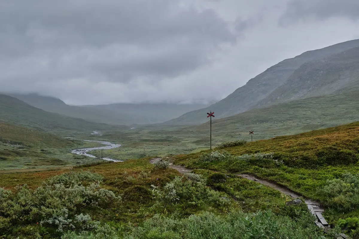 Sentier de randonnée montant vers un sommet volcanique avec panaches de vapeur