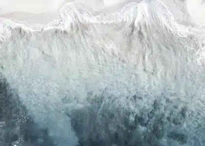 Vue aérienne d'un lagon turquoise bordé de mangrove et d'une crête volcanique boisée en arrière-plan