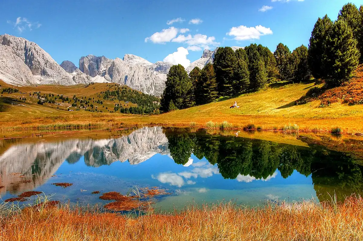 Prairie d'altitude et lac de montagne avec massif rocheux en arrière-plan
