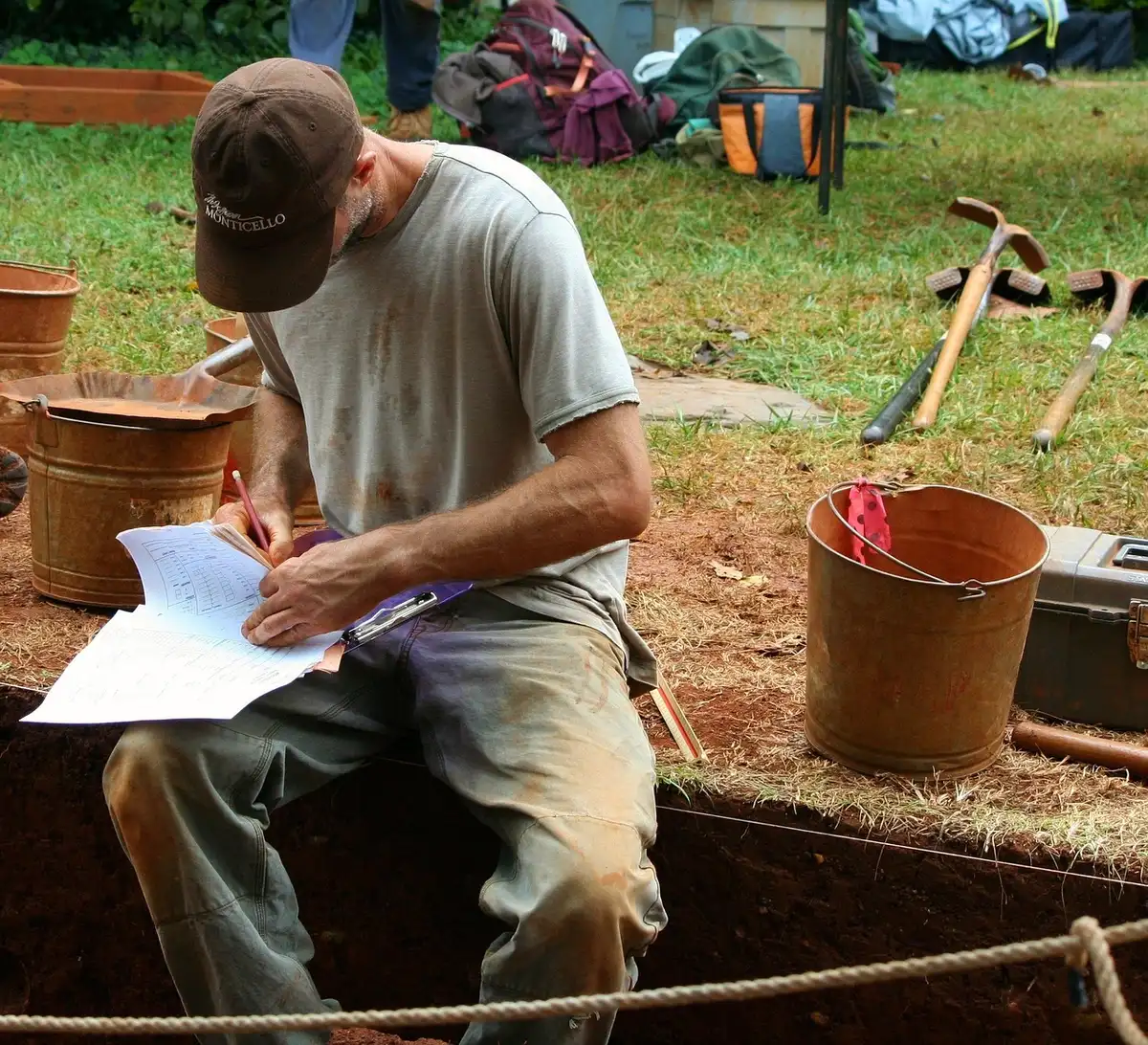 Fouille archéologique avec outils de mesure et fragments de céramique dans une tranchée