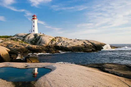 Vue diurne d'une côte rocheuse avec un phare lointain, un quai en bois et des randonneurs